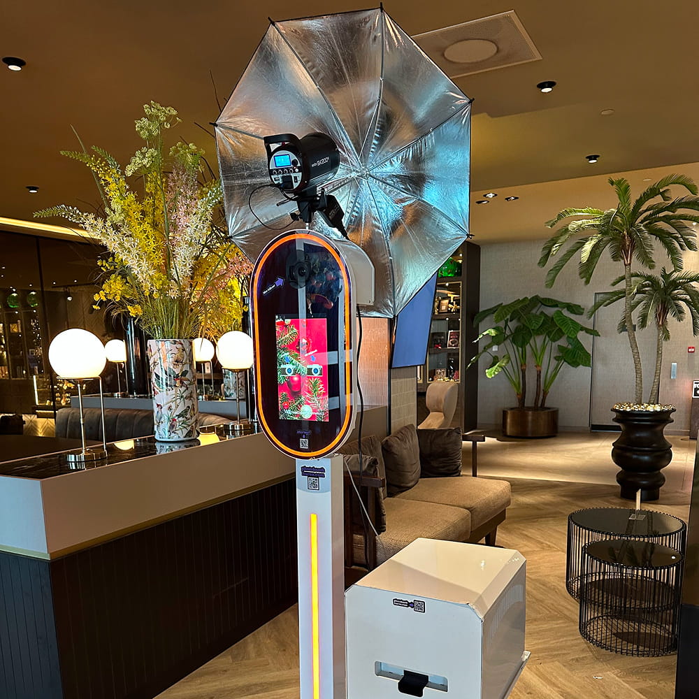 Luxe photobooth zuil in een hotellobby met oranje randverlichting