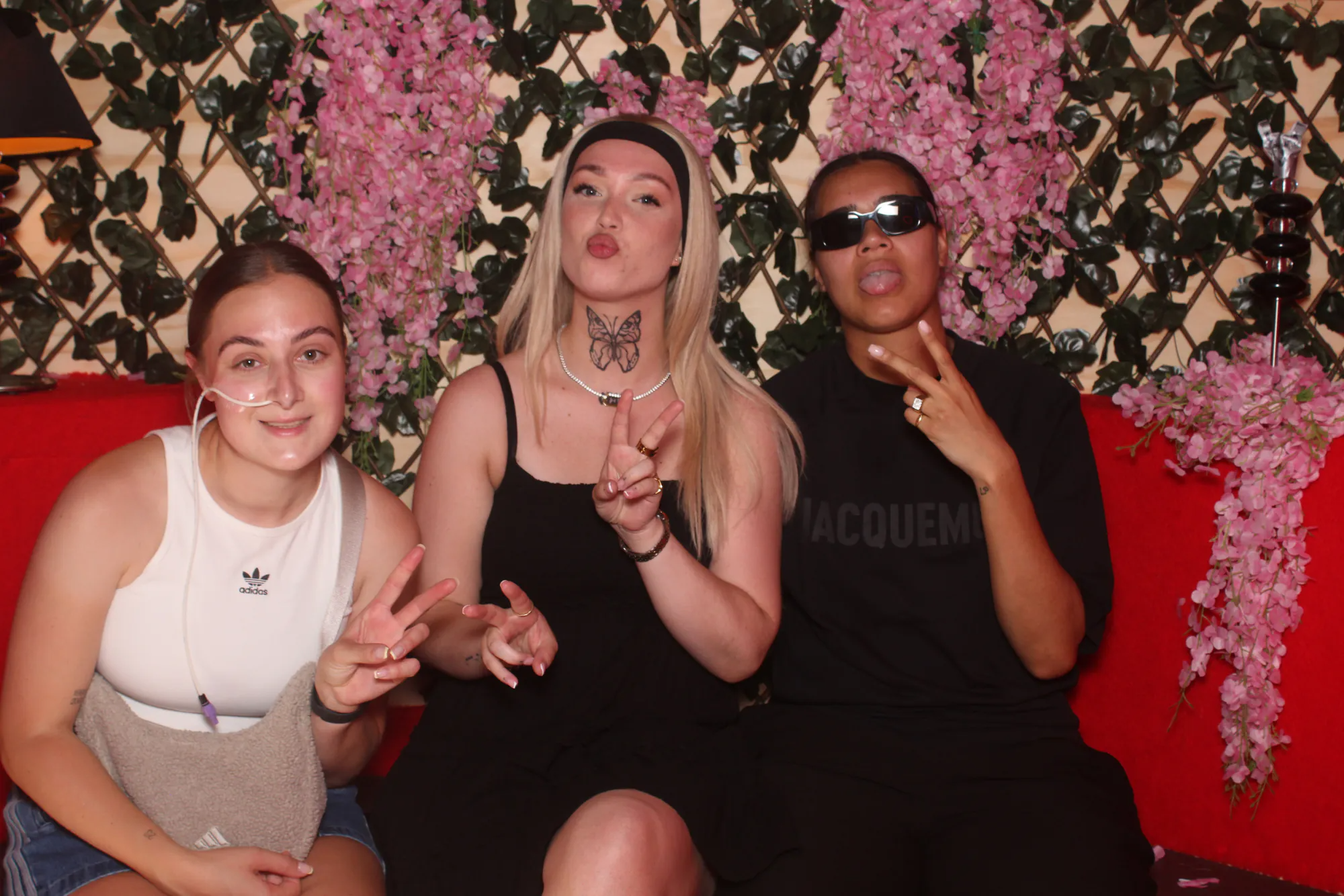 Drie gasten in de photobooth met bloemenwand